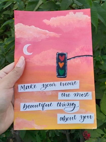 A whimsical painting featuring a traffic light with hearts instead of circles, set against a pink and yellow sky. The quote reads, "Make your heart the most beautiful thing about you."