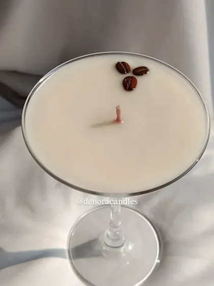 An elegant martini glass candle with layers of coffee-colored wax, topped with three coffee beans.