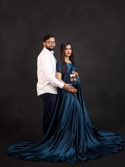 A classic couple's portrait in a deep teal satin gown. Holding the tiny baby shoes is a sweet reminder of the little one they are so excited to meet.