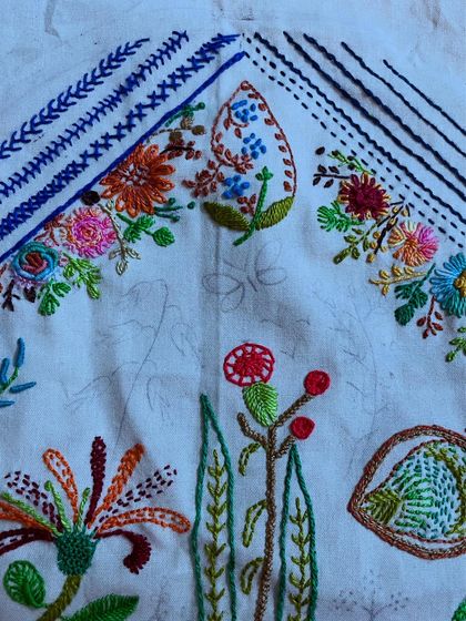 The freestyle hoop art project nearing completion. The combination of different stitches and colors creates a vibrant, imaginary garden.