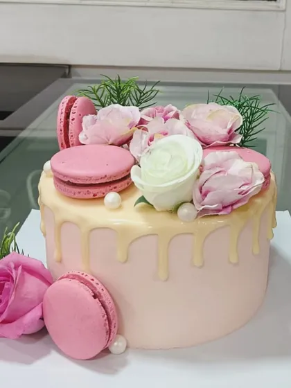 An elegant pink drip cake adorned with fresh roses and delicate macarons. The white chocolate drip adds a touch of luxury, making this a popular choice for birthdays, anniversaries, and bridal showers.