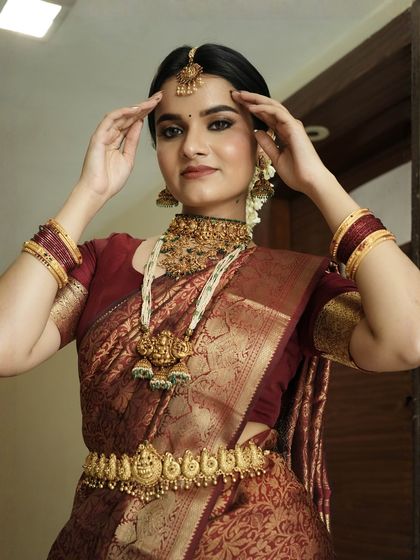 A playful and elegant pose that highlights the intricate jewellery and the bride's radiant smile. The makeup enhances her features without overpowering her natural beauty.