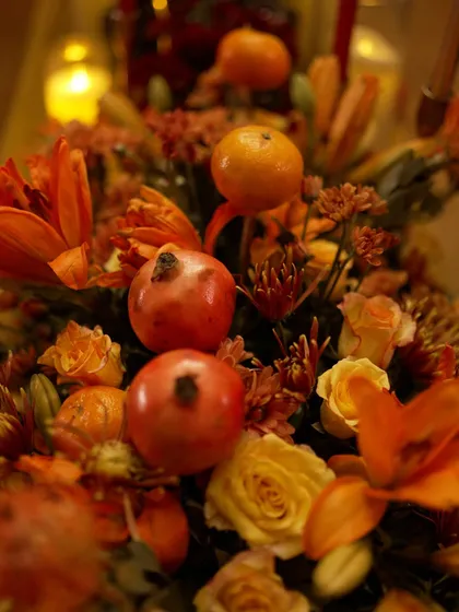 A centerpiece from the speakeasy theme, incorporating whole oranges and pomegranates into the fiery orange and red floral arrangement.