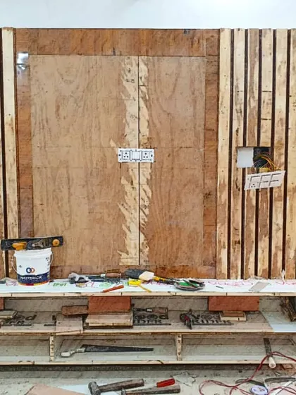 An unfinished view of a custom TV panel being built. This behind-the-scenes shot shows the raw wooden framework and paneling before the final finishing is applied.