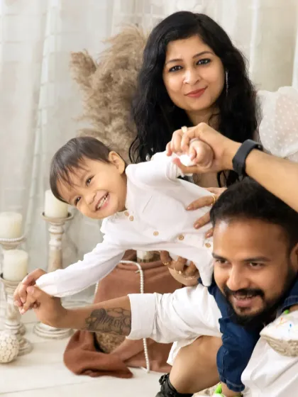 A fun and energetic shot of a little boy enjoying a shoulder ride with his dad, while his mom holds on, all laughing together.
