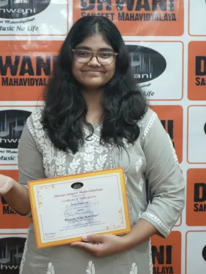 A student proudly holds her certificate and trophy.