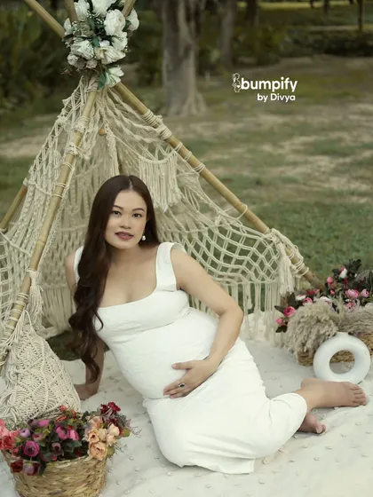 The mom-to-be smiles at the camera from her boho picnic setup. This shot showcases how we can bring a stylish, curated look to any outdoor location.