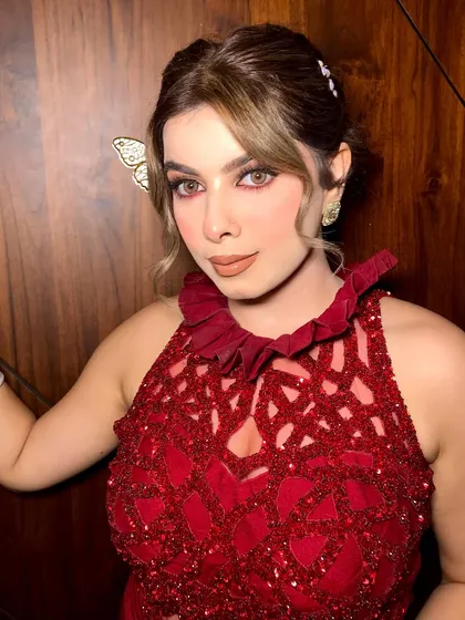 A statement look in a stunning red dress, featuring a chic knot bun and flawless glam.