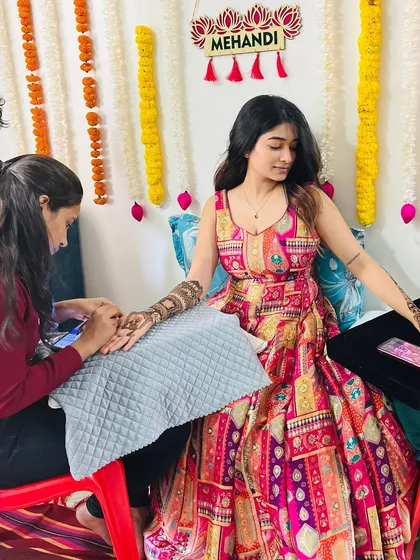 A candid moment from a mehendi ceremony, capturing the application process in a festive setting.