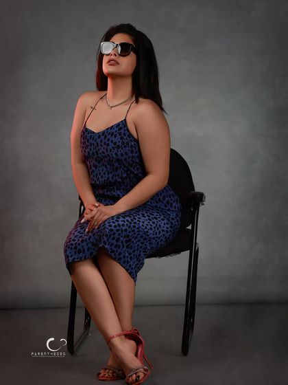 Sunglasses add an element of mystery and high fashion. This seated portrait uses subtle red-gel lighting to add warmth and dimension against the cool grey backdrop.
