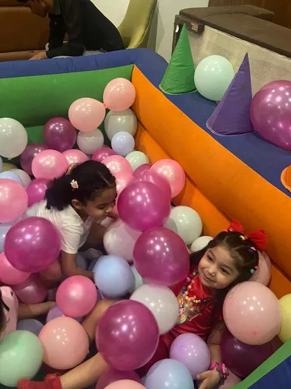 Two young girls having a great time in a ball pit filled with pastel-colored balls, part of a Unicorn-themed birthday party setup.