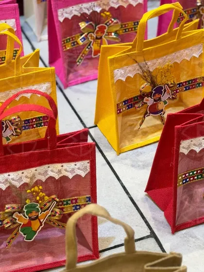 Bright and cheerful jute bags for Lohri gifting. These red and yellow bags are decorated with festive motifs, perfect for return favors.