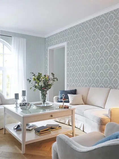 An elegant living room featuring a light blue damask pattern from our Trianon collection. Paired with a striped accent wall, it creates a classic and sophisticated French-inspired look.