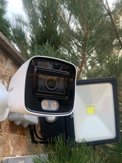 A Hikvision camera with a built-in spotlight installed on an exterior wall. This type of camera provides an extra layer of security by illuminating the area when motion is detected.