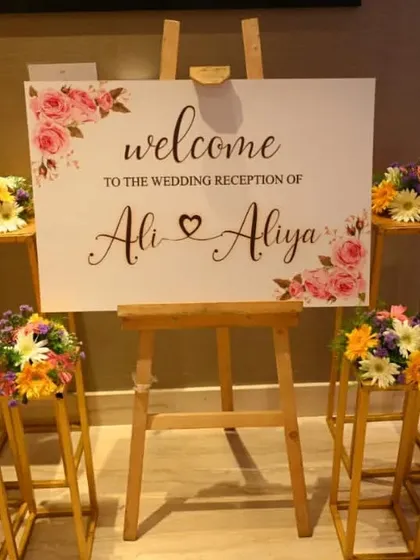 We create personalized welcome signs to greet your guests. This elegant wedding reception sign is displayed on an easel and surrounded by beautiful, fresh flower arrangements.