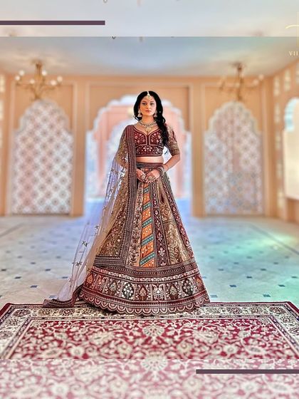 The bride stands majestically on a traditional rug, allowing the full length and design of this grand lehenga to be appreciated.