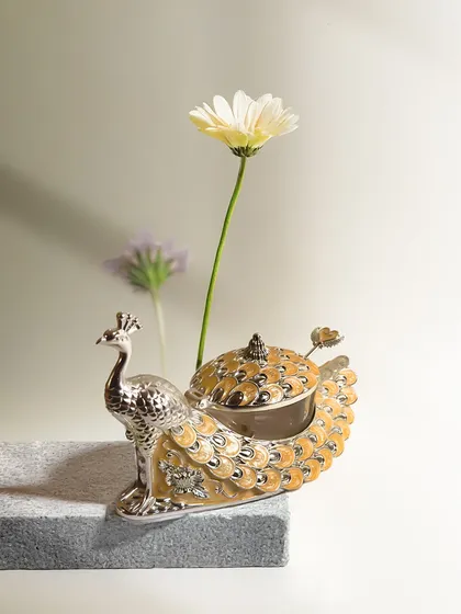 The same exquisite peacock dry fruit box, featured in a warm amber gold enamel. This shade brings a touch of sunny warmth and luxury, making it a striking accent for your home or a thoughtful gift.