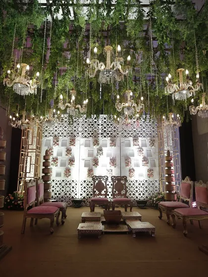 An indoor mandap with a ceiling of hanging greenery and chandeliers, blending natural elements with opulent lighting for a sophisticated and modern wedding.