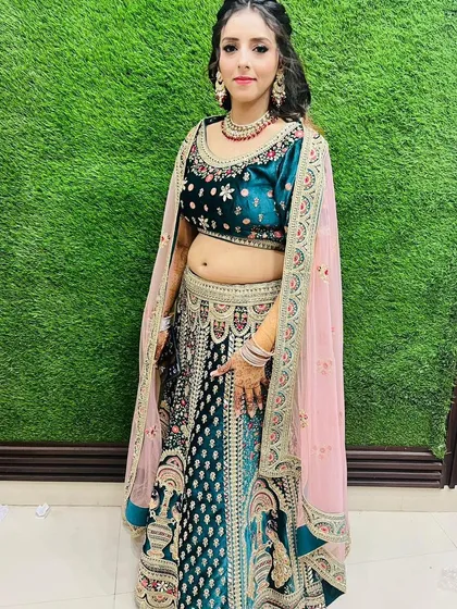 A happy client posing in the teal velvet rental lehenga. The contrast pink dupatta adds a beautiful pop of color to the overall look.