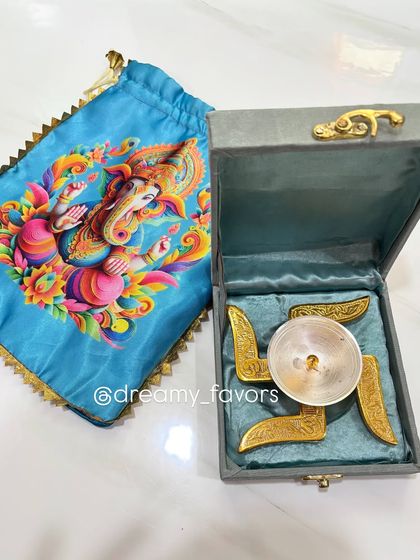 A beautiful Swastik Diya set in a velvet-lined box, accompanied by a blue Ganpati potli. This makes for a truly auspicious and elegant return gift during the Ganpati festival.