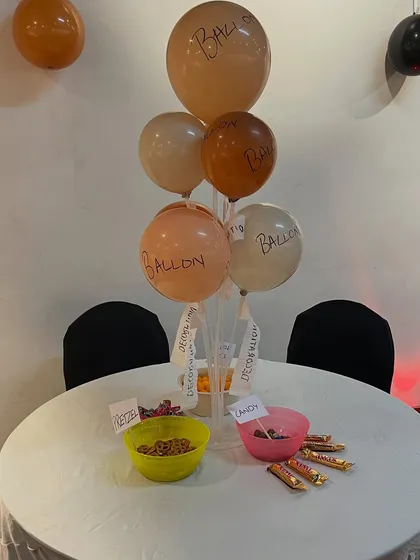 We included iconic inside jokes from the show, such as poorly labeled balloons, a "Rude that you're leaving" farewell banner, and a snack wall with the sign "Eat it, eat it".