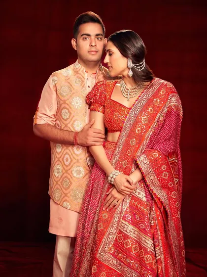 A beautiful couple's look featuring a stunning red Abu Jani Sandeep Khosla lehenga. The intricate detailing and rich color palette make it a perfect choice for a wedding celebration.