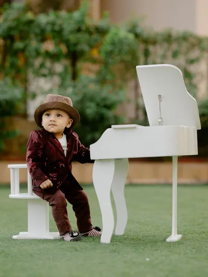 A tiny musician lost in thought. This portrait demonstrates one of my unique themed shoots, using props like this miniature white piano to create a stylish and imaginative setting.