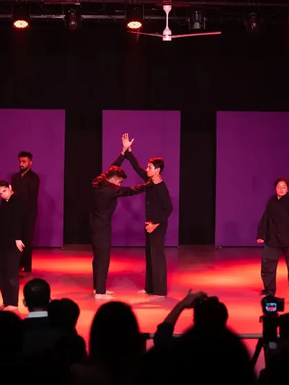 Students working together in a partner sequence during a stage performance. My choreography often includes intricate group dynamics and formations to create a visually rich experience.