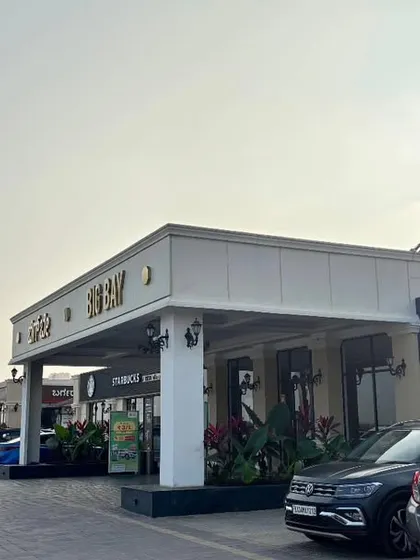 A daytime view of our campus, showing the main entrance and the Ajfan Dates & Nuts store, capturing the scale of India's largest food mall.