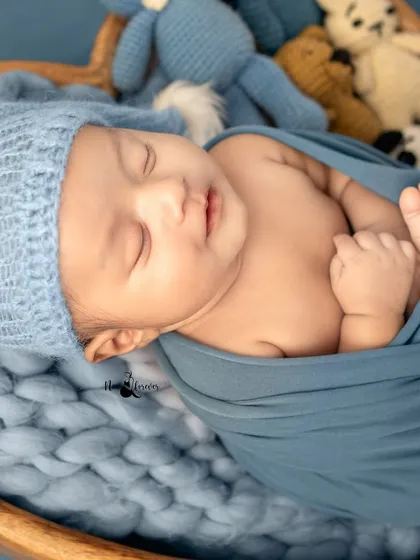 Tucked into a cozy blue wrap, this little one is dreaming peacefully. I use gentle wrapping techniques to keep babies comfortable and secure during their first photoshoot.