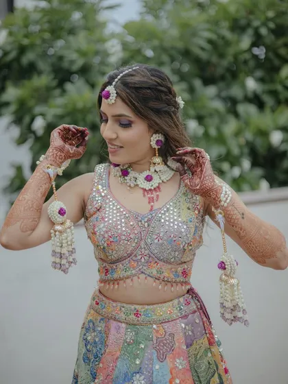 A bride in a colorful lehenga, wearing our purple and white floral jewellery set.
