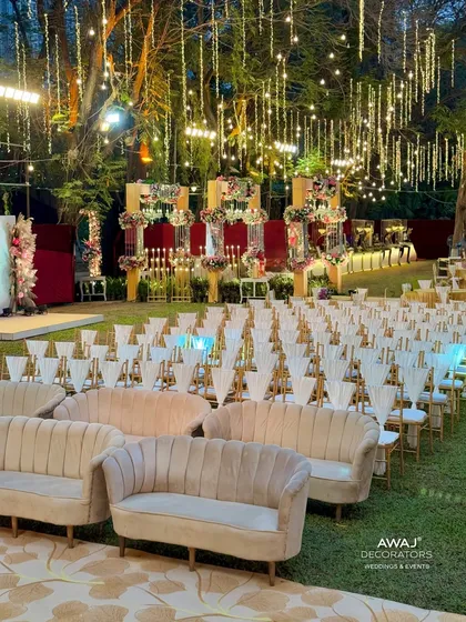 An outdoor seating arrangement with plush beige sofas and elegant chairs, set under a magical canopy of hanging lights.