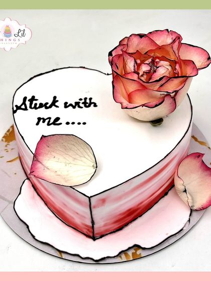 A romantic and artistic heart-shaped cake with the message "Stuck with me." The comic-book style outline and single rose create a unique look.