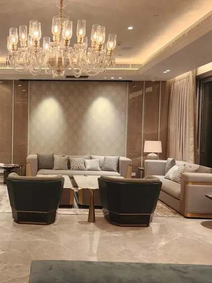 Another angle of the Sekhri residence, highlighting the interplay of light and texture. The grand chandelier and paneled walls create a sophisticated backdrop for the comfortable, modern furnishings.