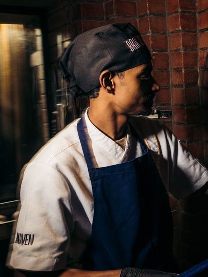 A member of our kitchen crew, focused on his craft. The dedication of our team is what ensures every pizza meets our high standards.