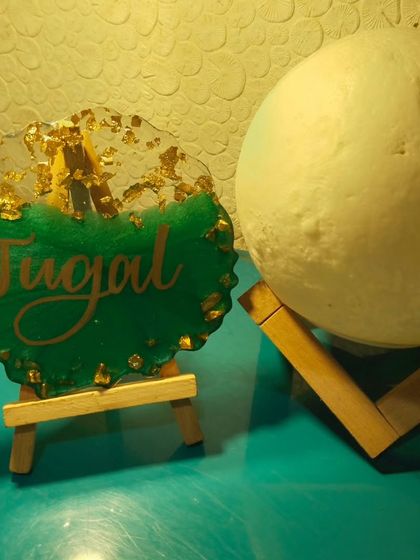 The finished name plaque displayed on a mini easel, next to a moon lamp. It's a perfect addition to a desk or shelf.