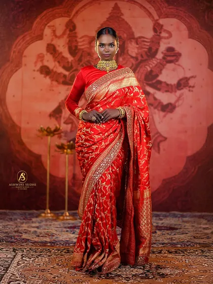 A full-length portrait demonstrating a powerful bridal look against a backdrop depicting Goddess Durga. This setup is perfect for creating culturally rich and divine-themed photographs.
