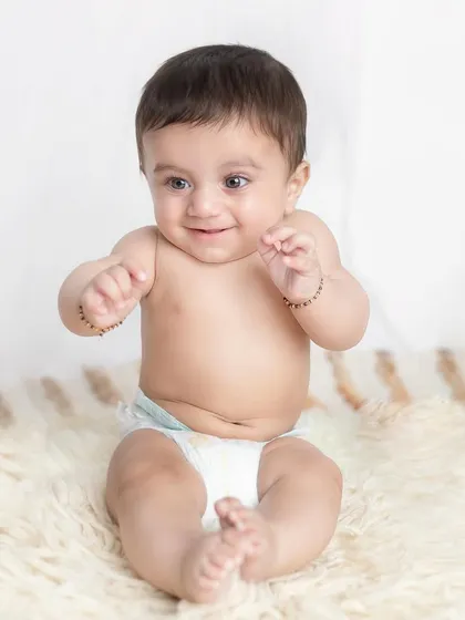 Cuteness overloaded! A simple, happy baby in a diaper is a timeless and classic portrait that captures their chubby rolls and sweet smile.