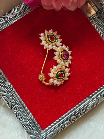 A beautiful Banu-style Nath with green and red stones. This design is inspired by the jewellery worn by Lord Krishna's consort and is a popular choice for festive occasions.