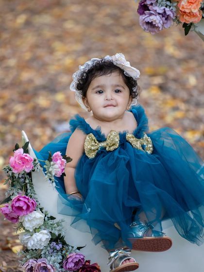 A sweet portrait of the birthday girl on her floral moon. The fallen leaves on the ground add a beautiful, autumnal texture to the scene.