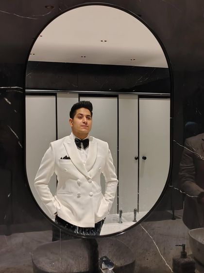 A mirror selfie capturing the essence of a gentleman. This client wears our crisp white double-breasted tuxedo jacket, a modern and stylish choice for a cocktail party.