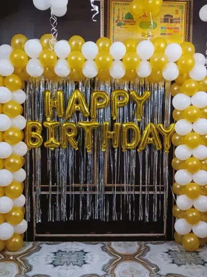 A classic balloon gate in gold and white with a "Happy Birthday" foil banner.