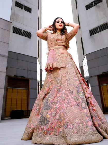 A stunning outdoor shot of a client in my pink peacock-motif lehenga, looking like a modern princess.