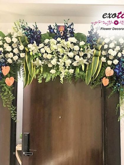 An elegant floral arch over a main door. This design features a sophisticated mix of blue orchids, white lilies, and lush greenery, creating a luxurious welcome.