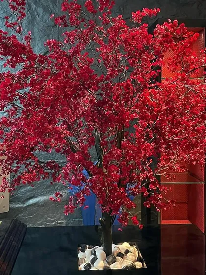 A striking artificial red maple tree used as a decorative piece inside an office. Artificial plants are a great zero-maintenance option for adding color and a touch of nature to indoor spaces.
