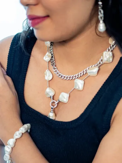 A detailed shot of our contemporary pearl and chain set. This jewellery combines classic pearls with a modern silver chain for a unique look that's perfect for a stylish party.
