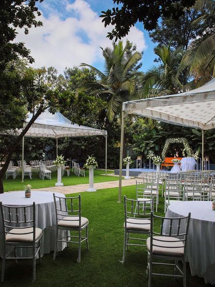 A collection of stunning wedding setups at The Farmhouse Collective. You can see the venue's versatility, from elegant morning ceremonies with floral mandaps to glamorous evening receptions with fairy lights and chic decor. This space is a blank canvas for your dream outdoor wedding in Bengaluru.