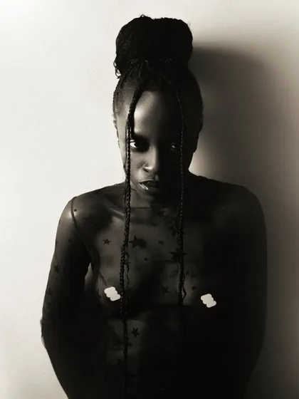 A tasteful and artistic semi-nude portrait. The sheer, star-patterned top and the model's direct gaze create an image that is both vulnerable and powerful.