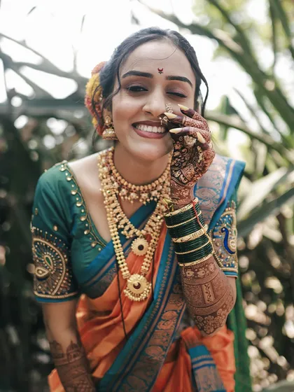 The infectious joy of a Maharashtrian bride. This candid portrait captures a genuine, playful smile, showcasing her beautiful traditional attire and intricate henna details.