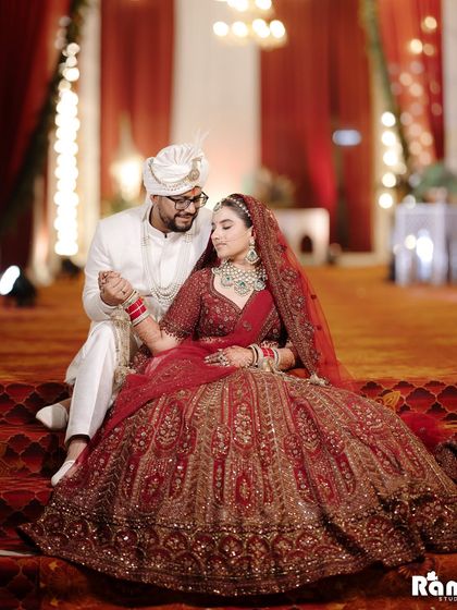 A sweet portrait of the couple seated on a stage, holding hands. The bride's magnificent lehenga and their gentle interaction make this a lovely shot.